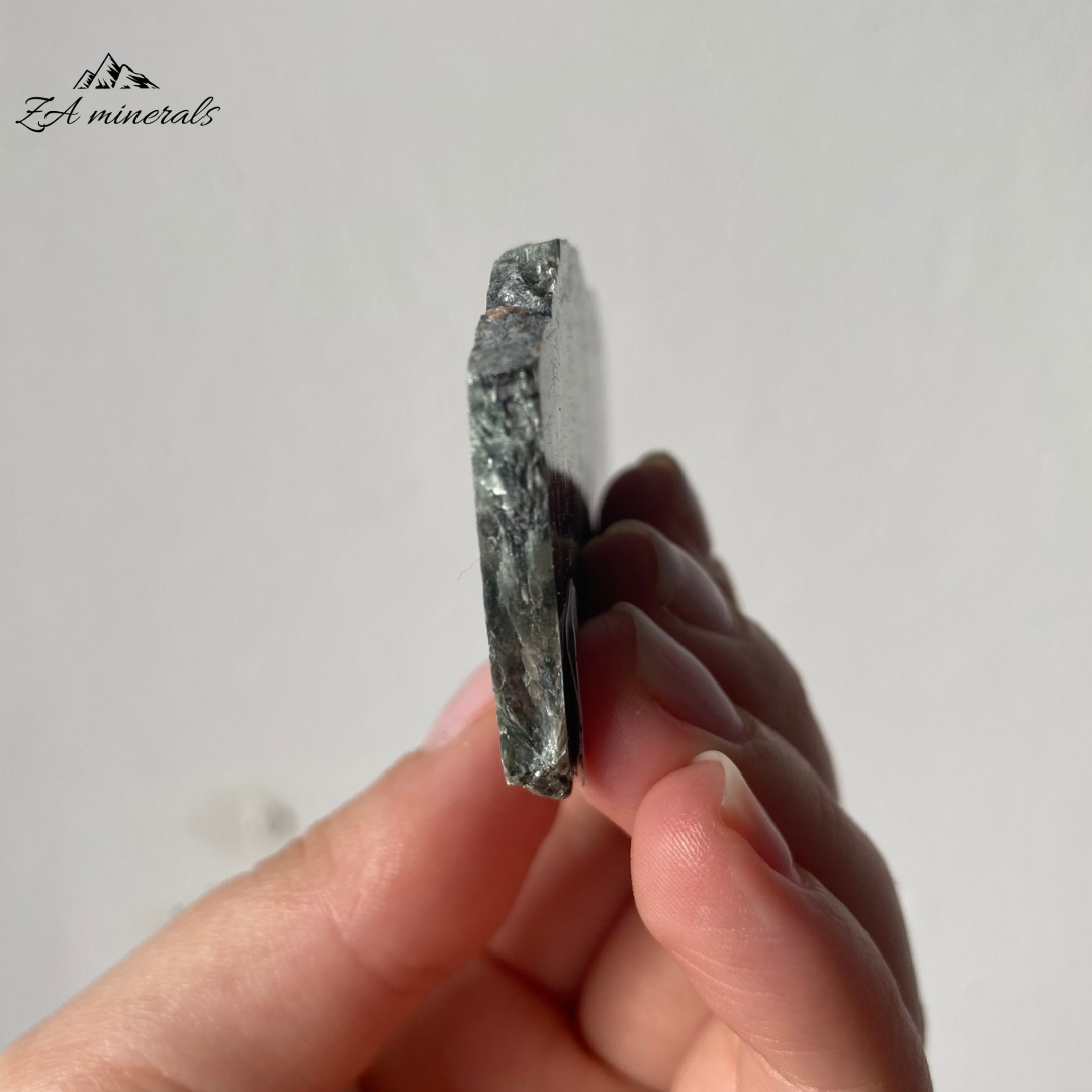 A variety of Clinochlore with a radiating/plumose structure. Gorgeous deep to light toned Greens. Shimmering silvery-white feather-like inclusions of chatoyant mica fibers. The face of the slice has been resined. The other side is sliced and natural.