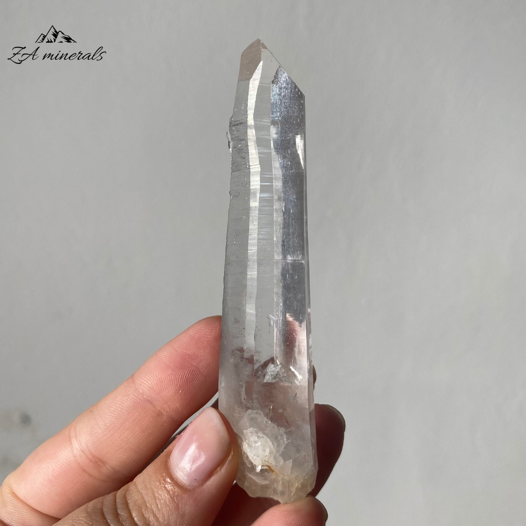 Vitreous, transparent, elongated prismatic Quartz. The quartz crystal is colourless. Quartz crystal is slightly bent towards the termination of the crystal. Contact damage predominantly to the base of the crystal body. Minor scattered chips to the crystal edges and faces.
