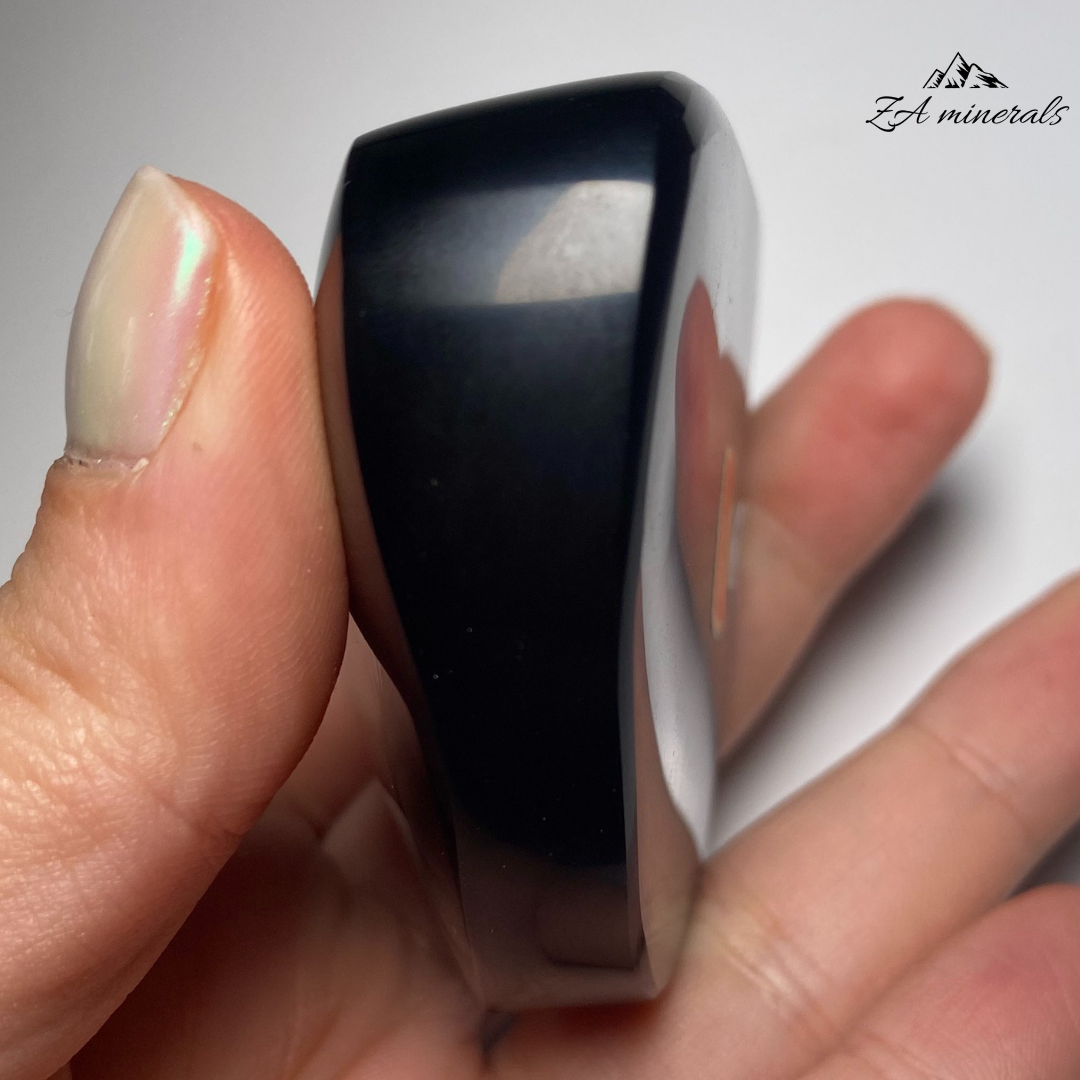 Smooth, opaque, polished heart of Obsidian. Obsidian has a black colour to it. Surface of the Obsidian heart exhibits a vibrant display of colours -blues and greens Little to no scratches or imperfections on the surface of the carving.