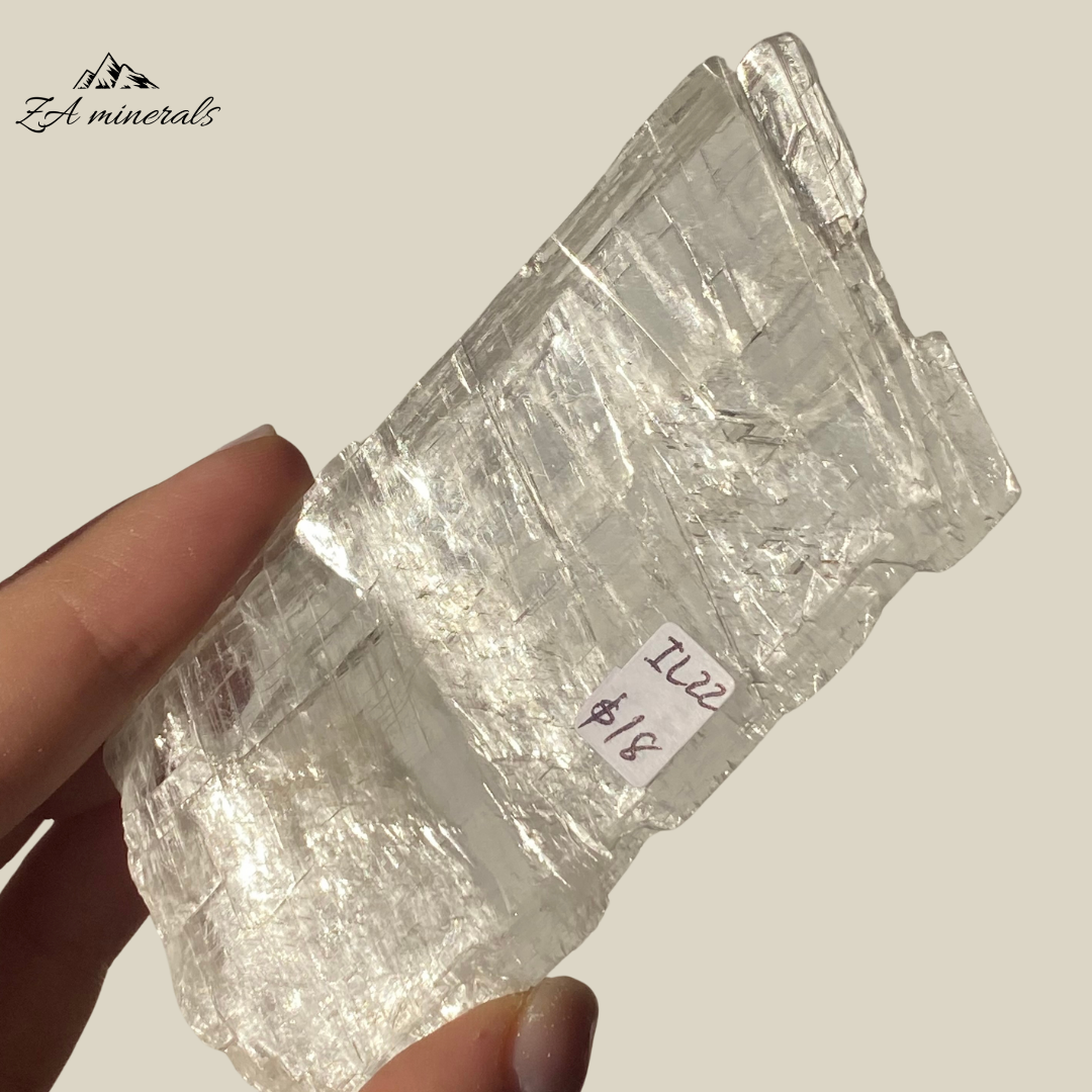 An amazing specimen of transparent and vitreous Selenite. Striations and internal stress can be seen inside the piece. The edges of the slice are rough. Rainbow inclusions can be seen in between the layers of the Selenite.