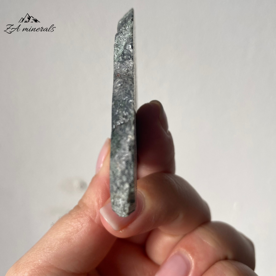 A variety of Clinochlore with a radiating/plumose structure. Gorgeous deep to light toned Greens. Shimmering silvery-white feather-like inclusions of chatoyant mica fibers. The face of the slice has been resined. The other side is sliced and natural.