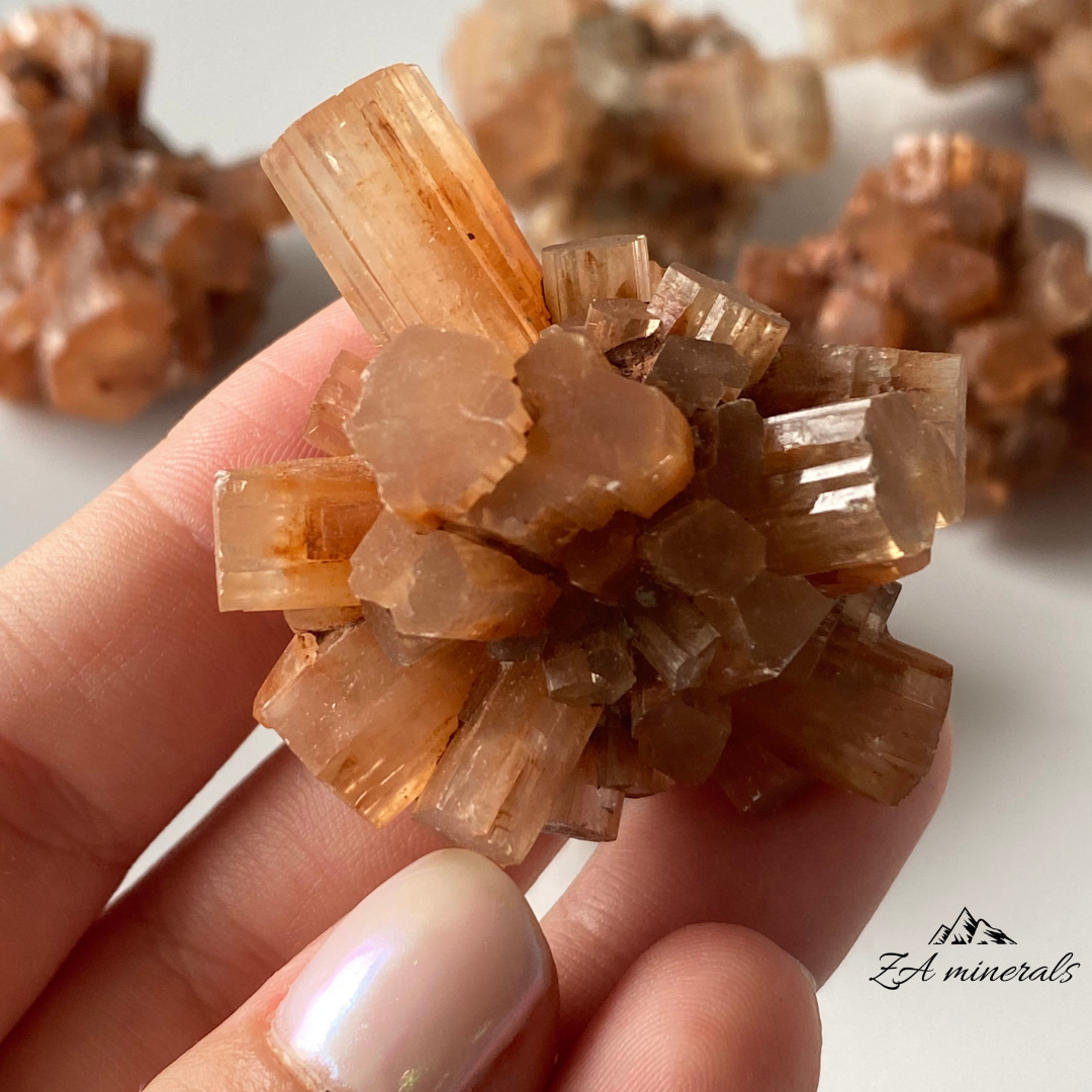 Vitreous, intergrown, orthorhombic Aragonite crystals. Aragonite has a lovely orange to colourless colour present. Aragonite has a pseudohexagonal trillings crystallized habit, in the form of elongated prismatic crystals. Contact damage to the crystals closest to the perimeter of the specimen.