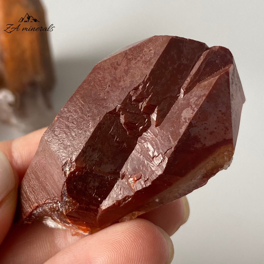 Prismatic, vibrant red toned Ferruginous Quartz. Some of the quartz crystals have a matte luster whilst other have a sub-vitreous lustre. The red colours of the ferruginous quartz crystals ranges between a bright red-orange to a deeper red-maroon tone. Hematite or an iron-rich mineral has developed on the surface of the quartzes. Some of the Quartez have the hematite or iron-rich mineral included. Scattered chips to the edges of the crystals and contact damage is present. 