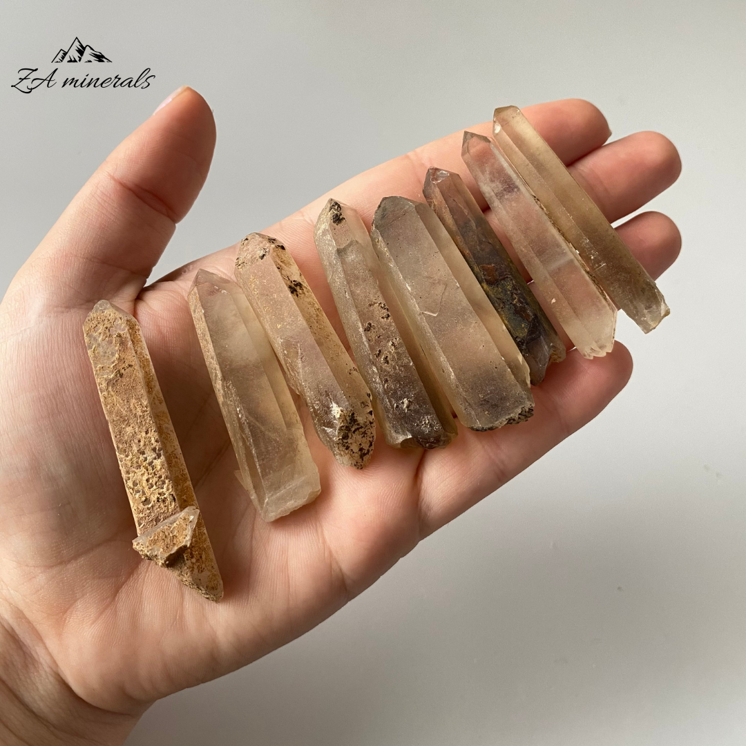 Matte, translucent to transparent, prismatic Quartz crystals. The majority of the Quartz is colourless. Subtle brown-smoky zoning can be seen at the bases of the Quartz crystal which moves slightly up the crystal bodies - like an ombre. Iron-rich coatings can be seen on the surface of the crystals. Scattered chips to the edges of the crystals and contact damage is present. 
