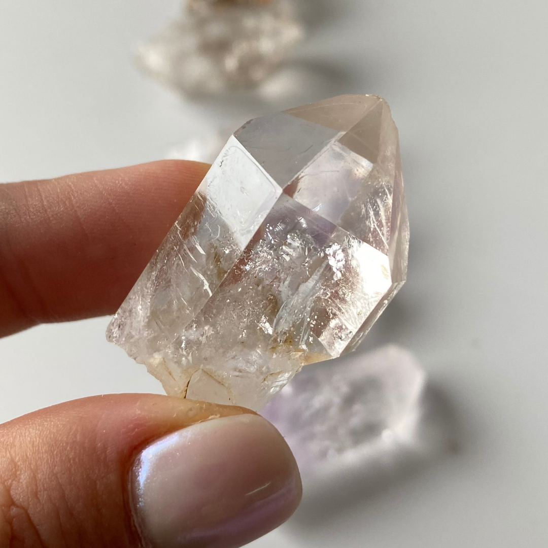 Vitreous, transparent to translucent, prismatic Quartz crystals. Subtle lavender-Amethyst zoning can be seen in three (3) of the Quartz crystals. One (1) of the Quartz crystals has a moving enhydro water bubble. Three (3) of the Quartz are clear and colourless. Three (3) of the Quartz have lovely saturated Smoky zoning present. Chip to the termination of the one amethyst Quartz. Damage to the base of the crystals. Minor scattered chips to the crystal edges.