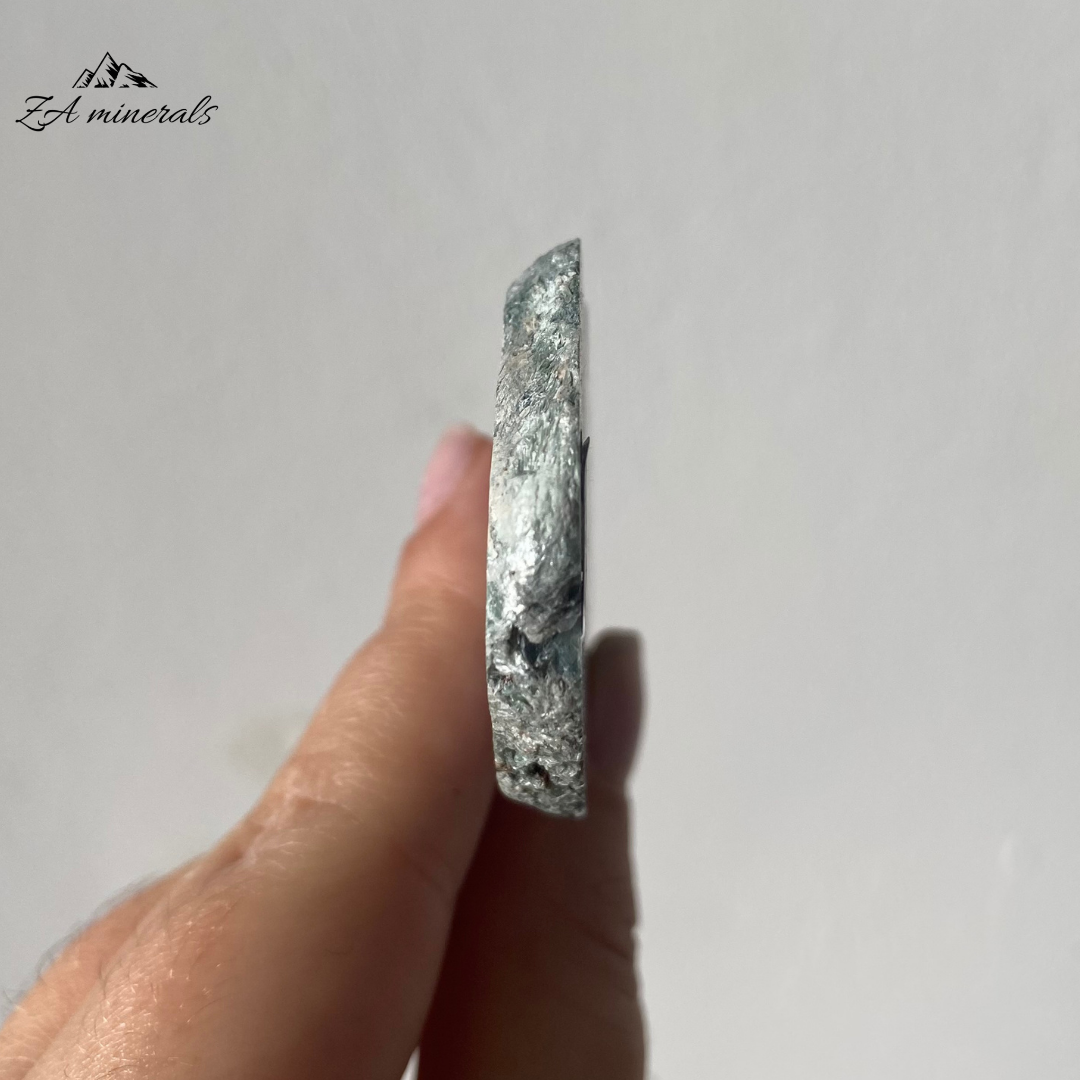 A variety of Clinochlore with a radiating/plumose structure. Gorgeous deep to light toned Greens. Shimmering silvery-white feather-like inclusions of chatoyant mica fibers. The face of the slice has been resined.  The other side is sliced and natural.