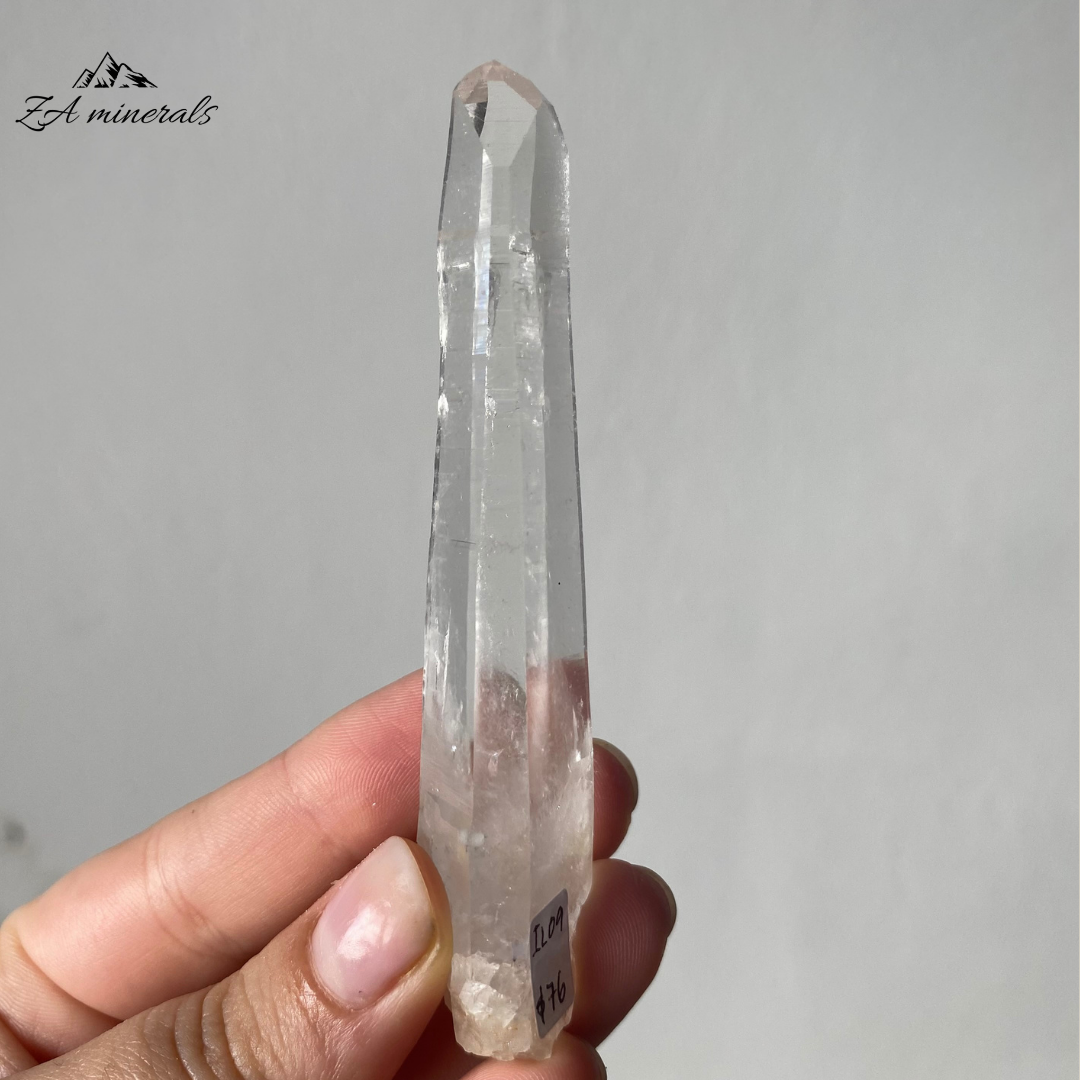Vitreous, transparent, elongated prismatic Quartz. The quartz crystal is colourless. Quartz crystal is slightly bent towards the termination of the crystal. Contact damage predominantly to the base of&nbsp; the crystal body. Minor scattered chips to the crystal edges and faces.