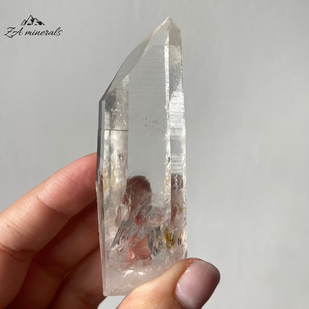 Vitreous, transparent, elongated prismatic Quartz. This quartz is slightly chunky. The termination has a large Isis Face.  Contact damage predominantly to the base of the crystal body. Minor scattered chips to the crystal edges and faces.