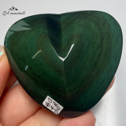 Smooth, opaque, polished heart of Obsidian. Obsidian has a black colour to it. Surface of the Obsidian heart exhibits a&nbsp; display of colours -vibrant green to blue tones. Little to no scratches or imperfections on the surface of the carving.