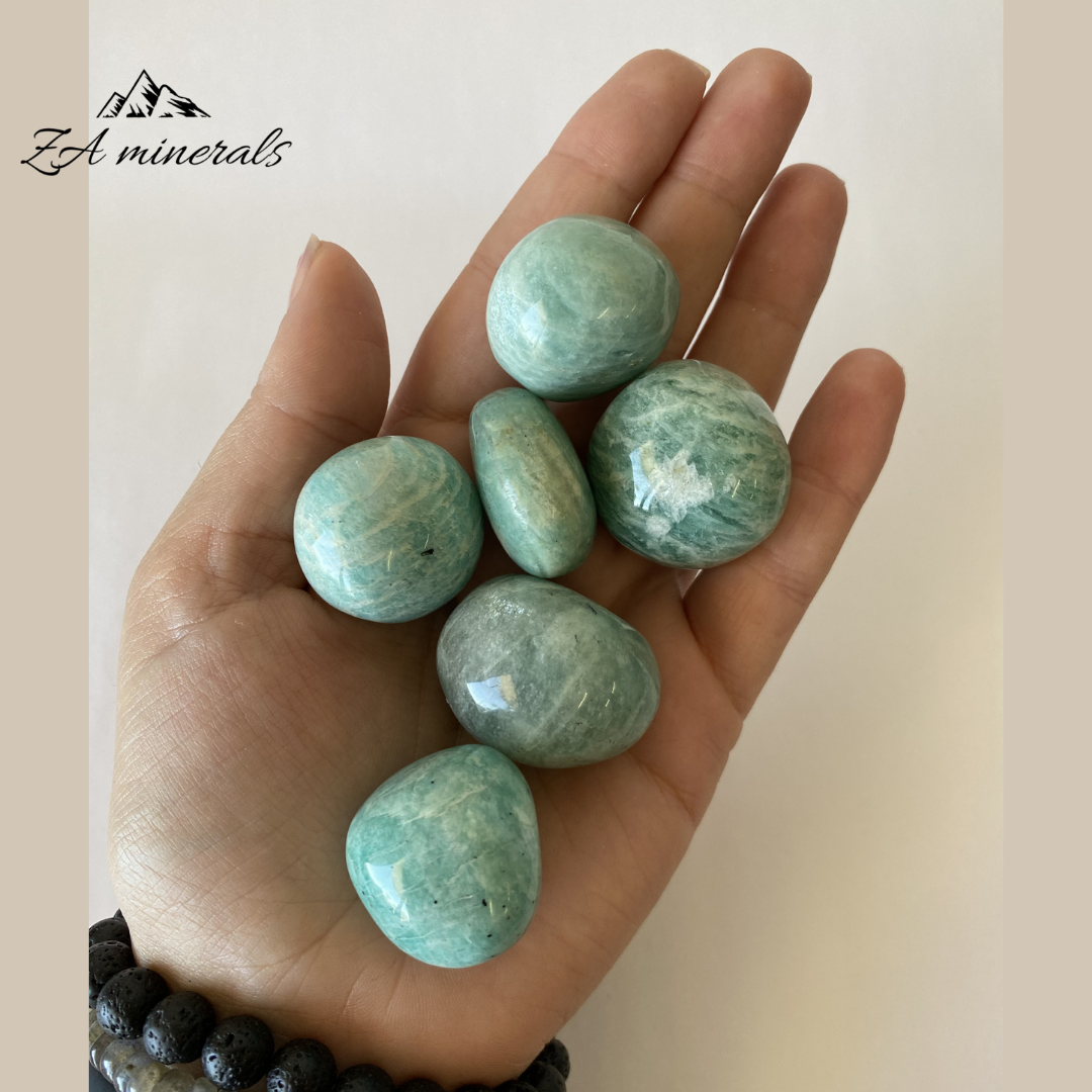 Hand holding greenish-blue stones with 'ZA minerals' branding.