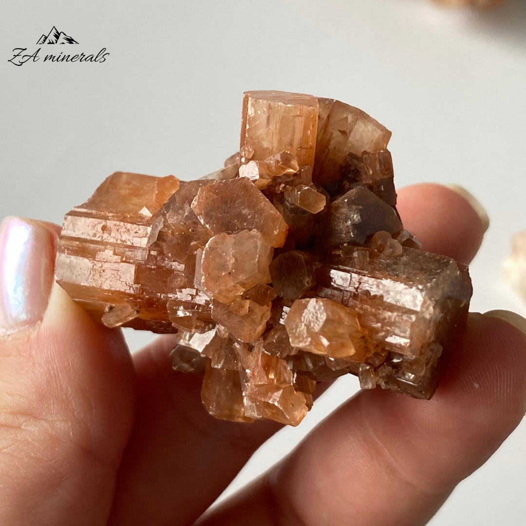 Vitreous, intergrown, orthorhombic Aragonite crystals.&nbsp; Aragonite has a lovely orange to colourless colour present. Aragonite has a pseudohexagonal trillings crystallized habit, in the form of elongated prismatic crystals. Contact damage to the crystals closest to the perimeter of the specimen.