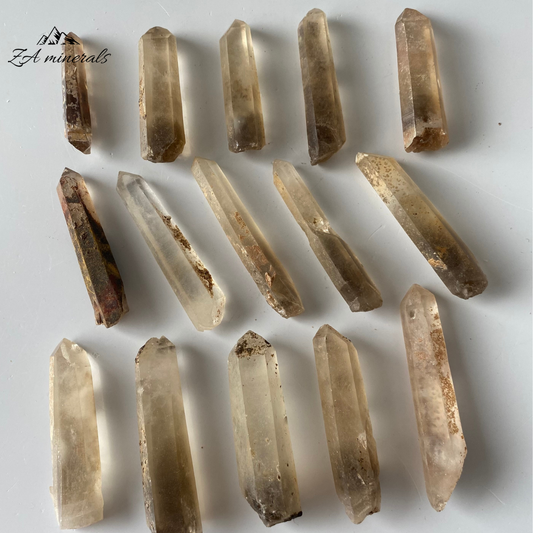 Matte, translucent to transparent, prismatic Quartz crystals. The majority of the Quartz is colourless. Subtle brown-smoky zoning can be seen at the bases of the Quartz crystal which moves slightly up the crystal bodies - like an ombre. Iron-rich coatings can be seen on the surface of the crystals. Scattered chips to the edges of the crystals and contact damage is present.&nbsp;
