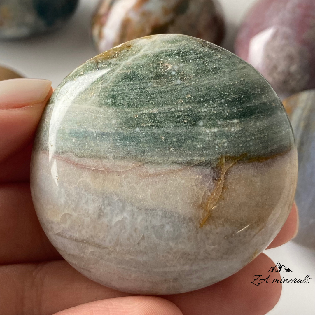 Smooth, opaque, polished Ocean Jasper Palmstones. These Ocean Jasper palmstones have captivating pastel hues that blend from one tone to another. Beautiful shades of blue- green, yellow to orange, deep red to maroon and pink to purple. Some of the palmstones have a flat surface whilst others are more rounded entirely. Minor scratches, vugs and fractures present.