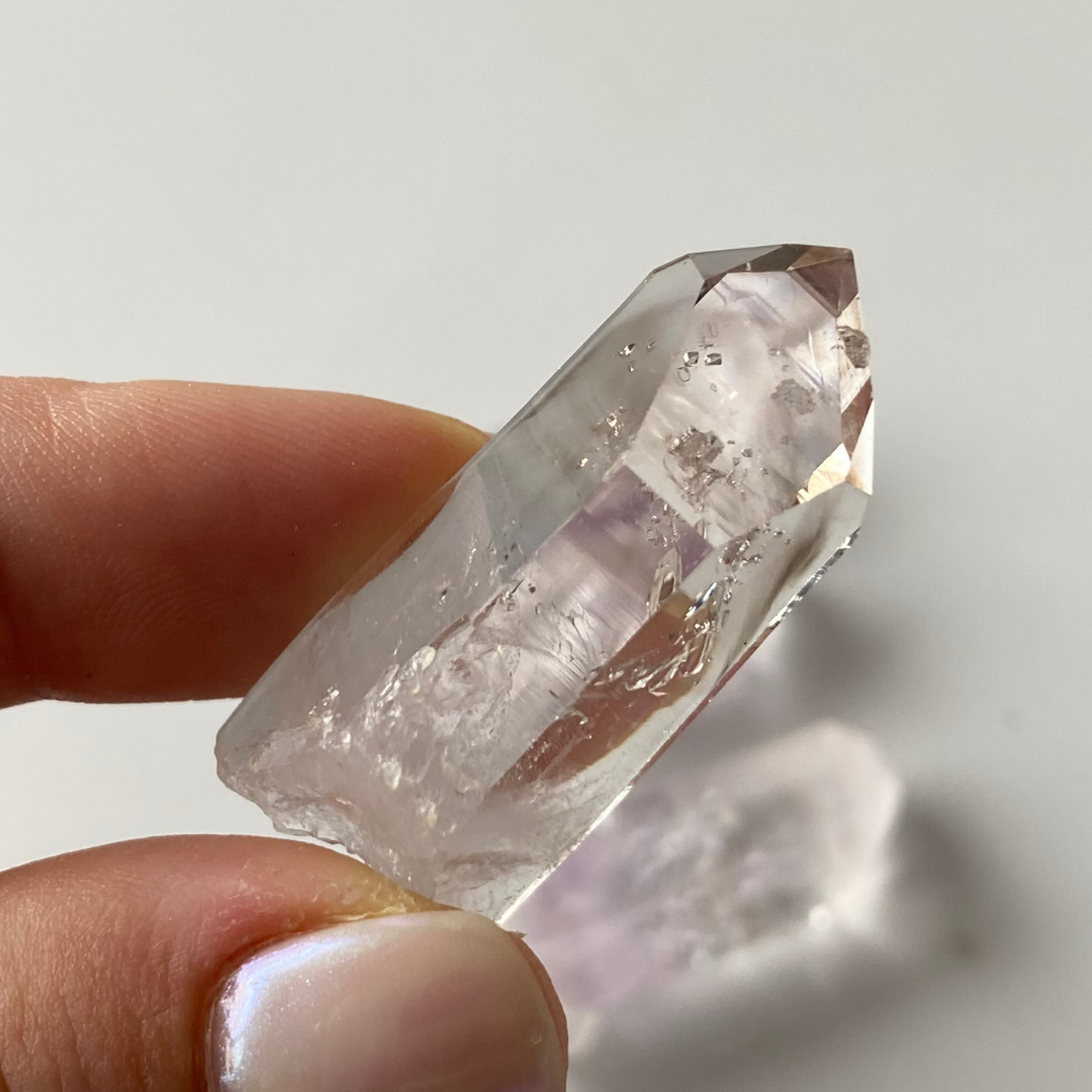 Vitreous, transparent to translucent, prismatic Quartz crystals. Subtle lavender-Amethyst zoning can be seen in three (3) of the Quartz crystals. One (1) of the Quartz crystals has a moving enhydro water bubble. Three (3) of the Quartz are clear and colourless. Three (3) of the Quartz have lovely saturated Smoky zoning present.  Chip to the termination of the one amethyst Quartz. Damage to the base of the crystals. Minor scattered chips to the crystal edges.